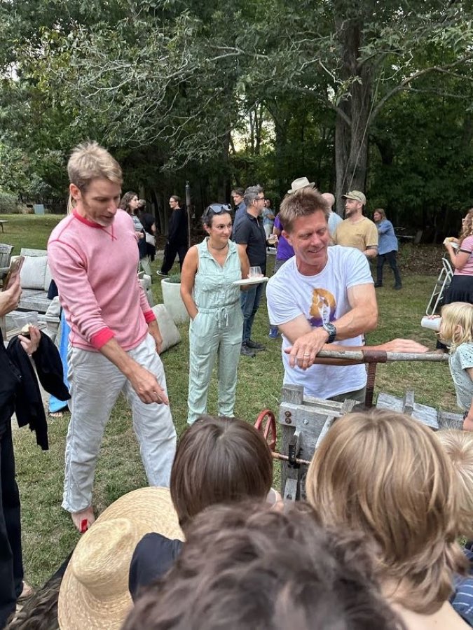 Turning the crank on the wooden cider press while kids watch